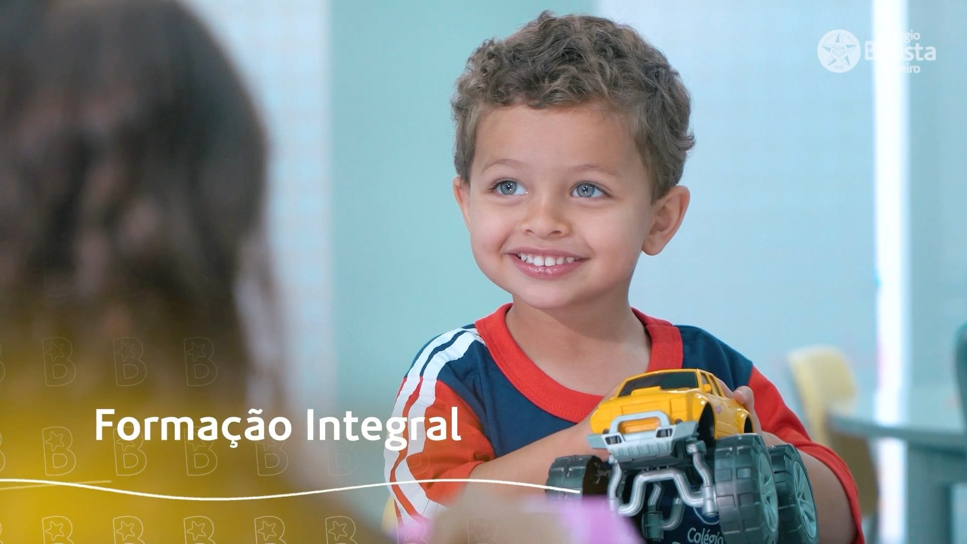 Criança sorrindo segura caminhão de brinquedo com texto Formação Integral ao lado. Educação criativa e divertida.